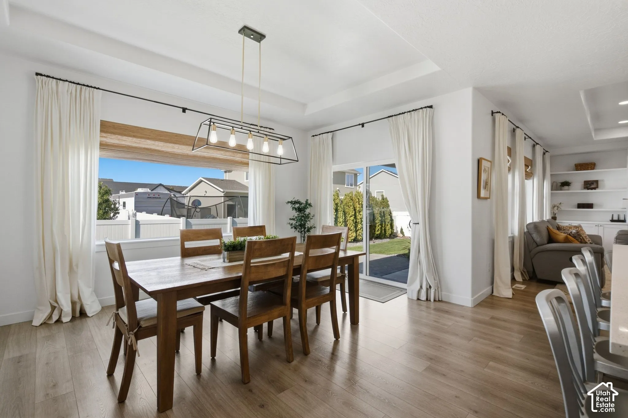 Wood-finish flooring, recessed ceiling, large framed window, sliding glass door, and built-in shelving
