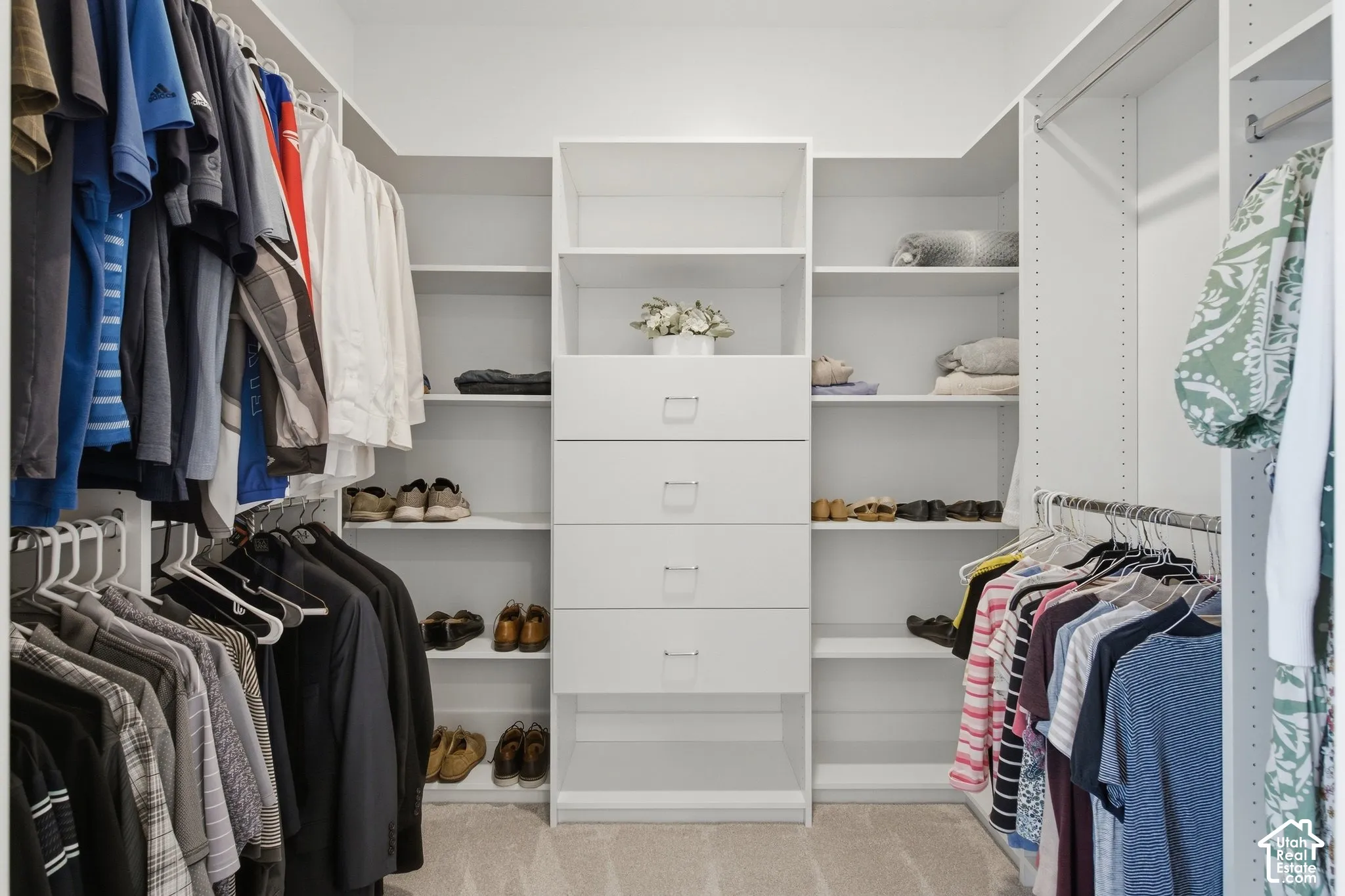 Custom white built-in closet system featuring multiple hanging rods, integrated shelving, and central drawer storage