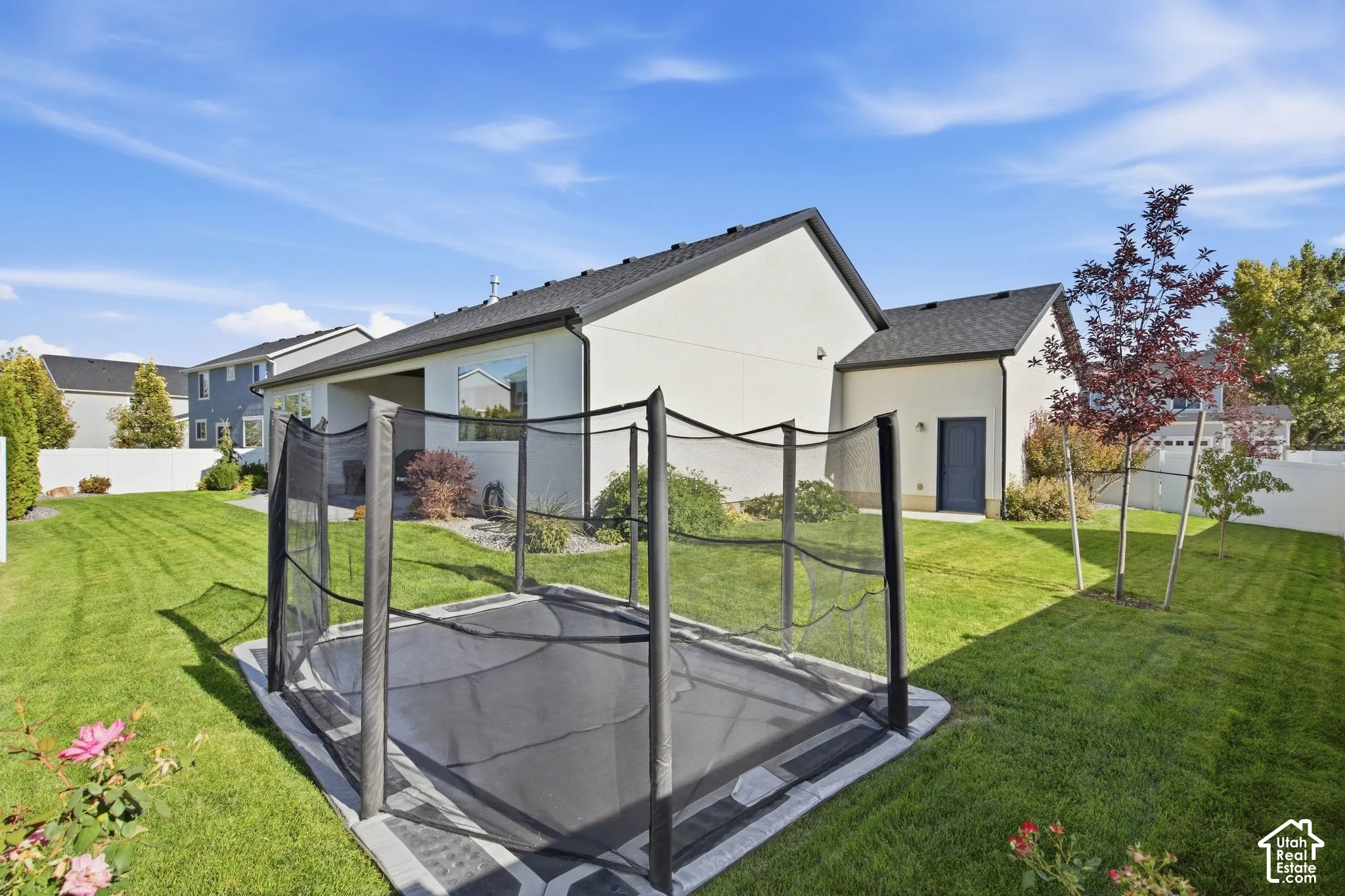 Expansive lawn area with a flush-mounted trampoline, perimeter fencing, and mature landscaping