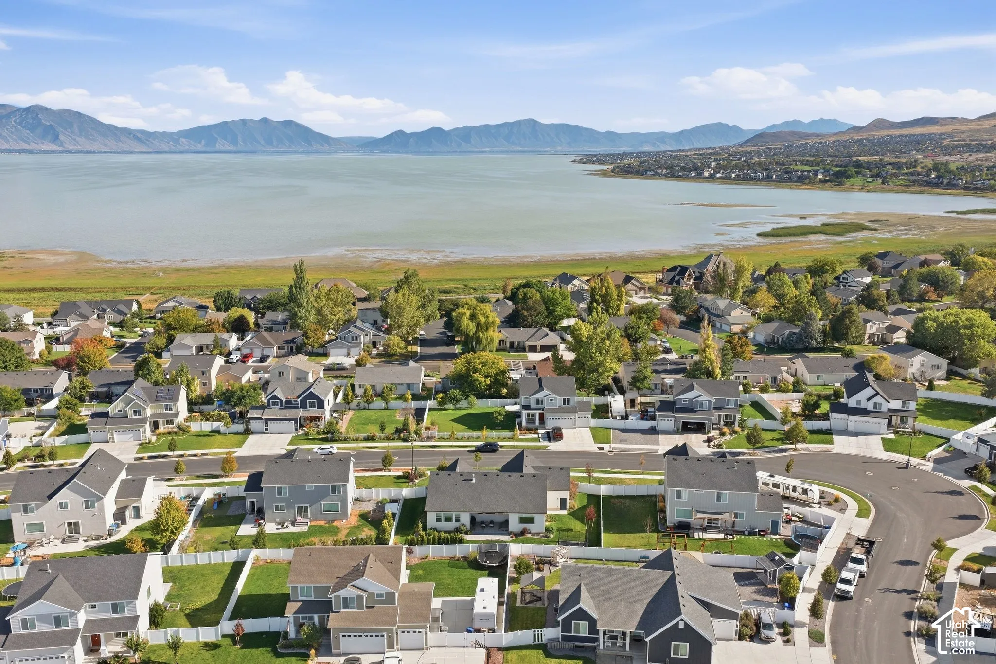 Aerial perspective showcasing a residential development, a large body of water, and distant mountains