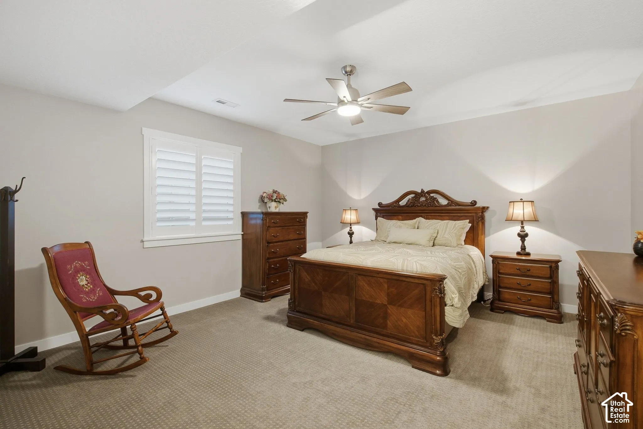 Carpeted room featuring a ceiling fan, crown molding, and window with plantation shutters