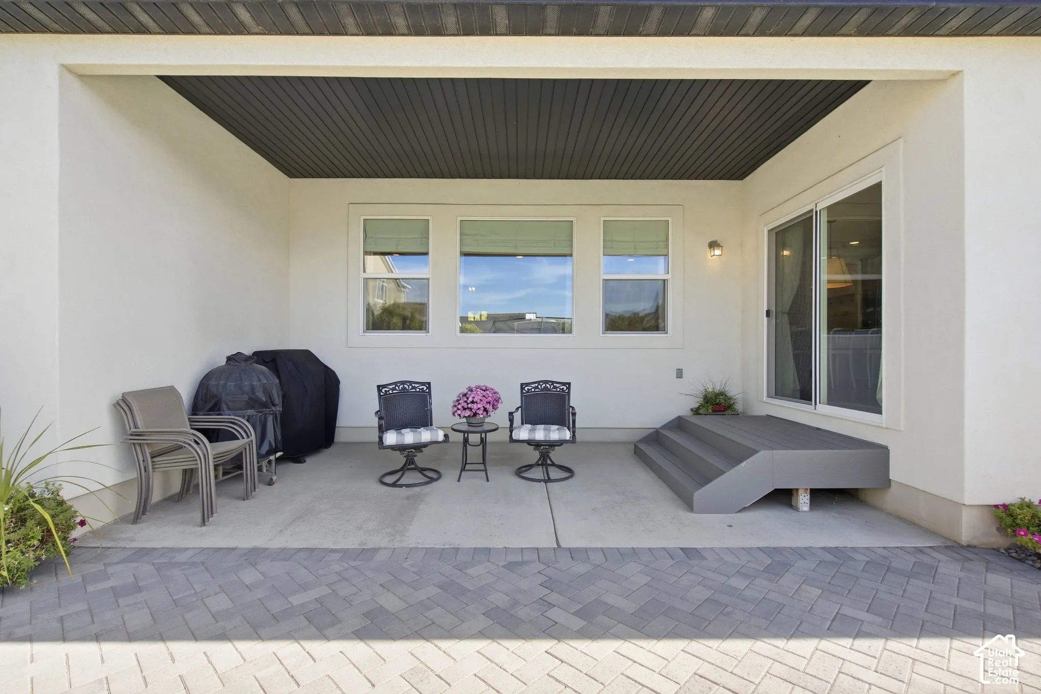 Covered patio featuring a slat wood ceiling, white stucco walls, and a paver stone surface