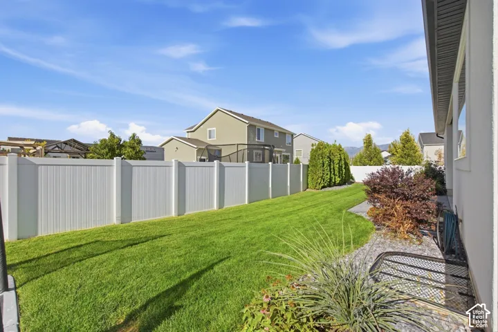 Expansive backyard featuring a manicured lawn, white privacy fencing, and established perimeter plantings
