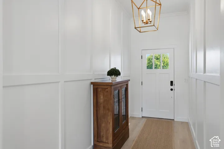White paneled walls, light wood-finish flooring, and a white entry door with glass paneling