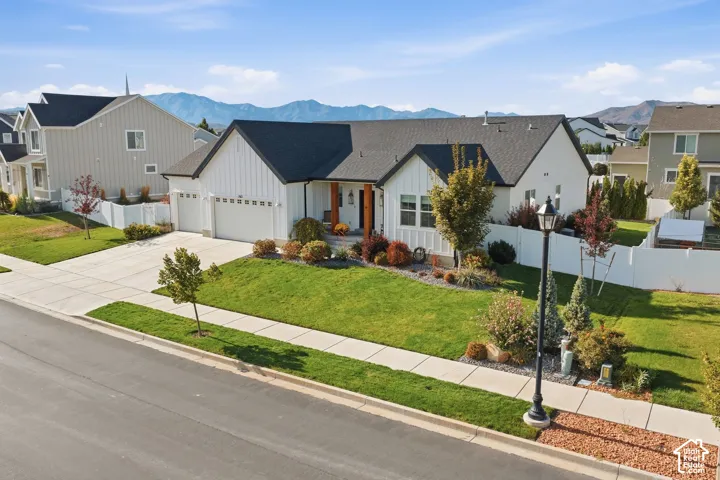 Modern farmhouse style exterior, two-car garage, concrete driveway, mature landscaping, and white privacy fence