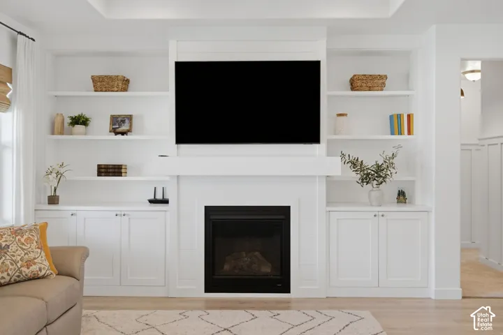 Built-in shelving and cabinetry framing a fireplace, with a wood-finish flooring