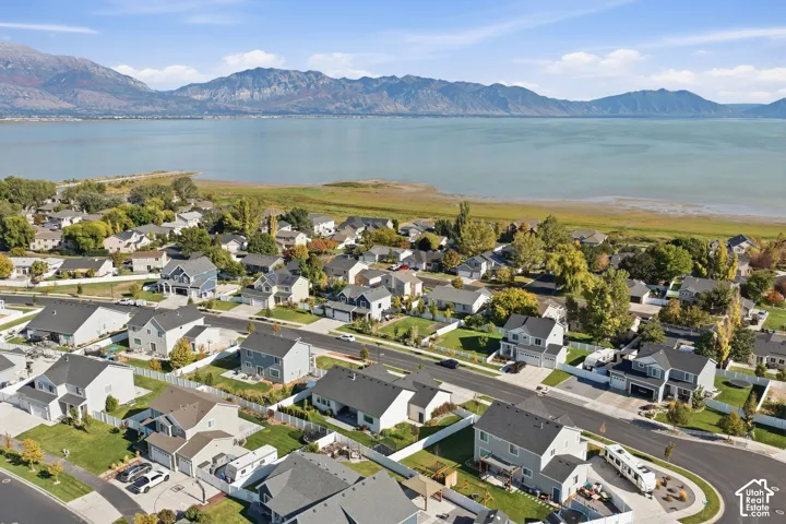 Residential neighborhood with mature trees, established landscaping, mountain backdrop, and waterfront access