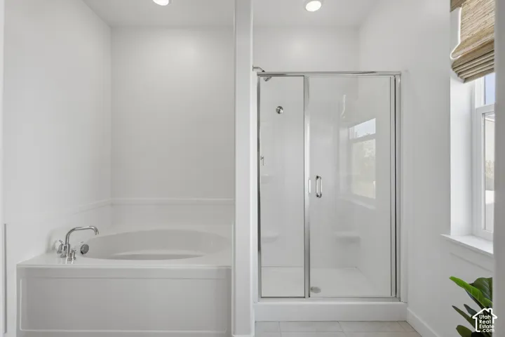 Built-in soaking tub with polished chrome fixtures, glass-enclosed shower, and recessed lighting