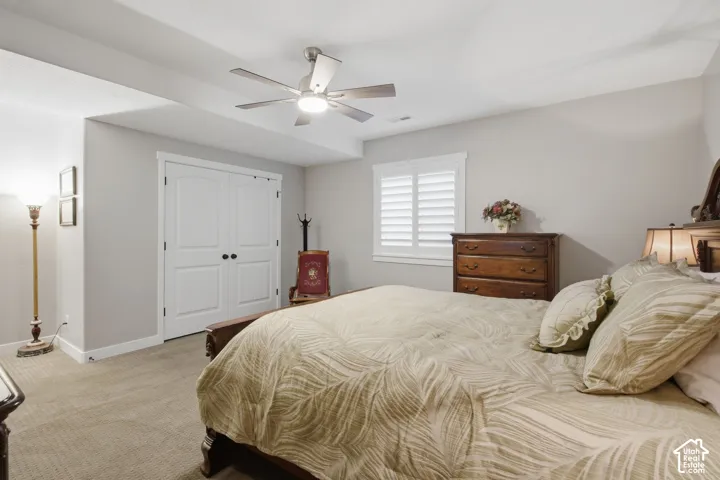 Carpeted flooring, recessed lighting, ceiling fan with integrated light, double-door closet with black hardware, and window with plantation shutters