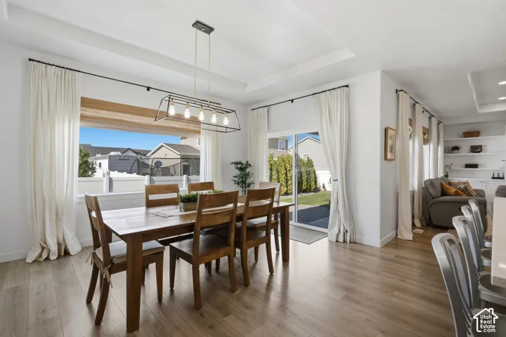 Wood-finish flooring, recessed ceiling, large framed window, sliding glass door, and built-in shelving