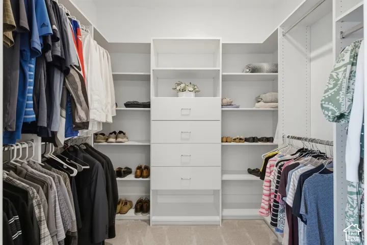 Custom white built-in closet system featuring multiple hanging rods, integrated shelving, and central drawer storage