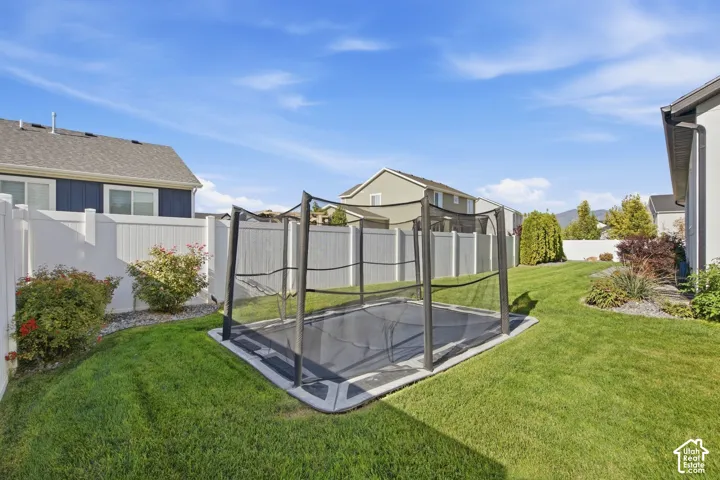 Expansive green lawn with established perimeter landscaping and a full privacy fence