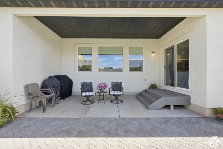 Covered patio featuring a slat wood ceiling, white stucco walls, and a paver stone surface