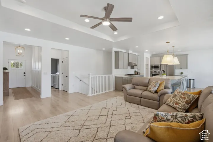 Open-concept living area with wood-finish flooring, a tray ceiling, and recessed lighting