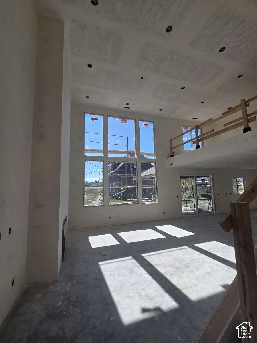 Expansive, high-ceilinged room featuring a multi-pane window wall, recessed lighting, a built-in fireplace, and a sliding glass door