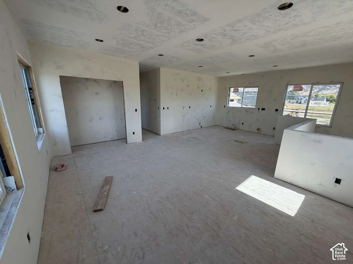 Recessed ceiling lighting, multiple windows, interior walls with drywall, partially finished interior, and an exposed subfloor
