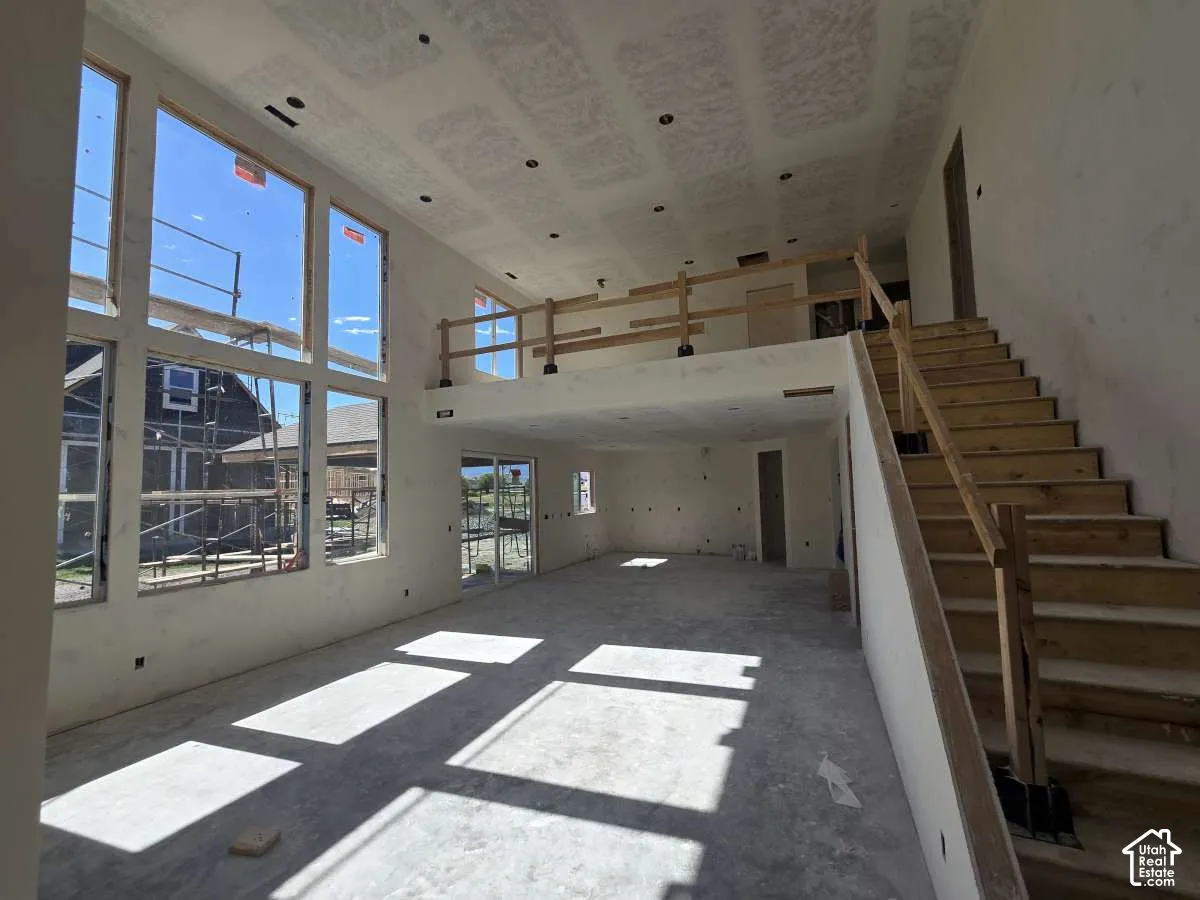 Two-story great room with soaring ceilings, a prominent staircase, and expansive windows