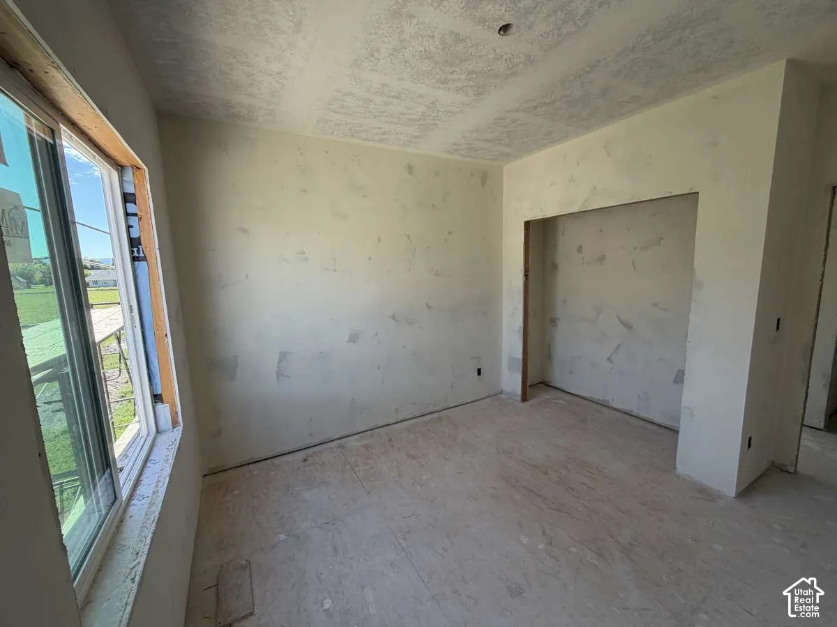 Unfinished interior space featuring a window, built-in wall niche, and unfinished flooring