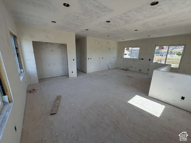 Recessed ceiling lighting, multiple windows, interior walls with drywall, partially finished interior, and an exposed subfloor