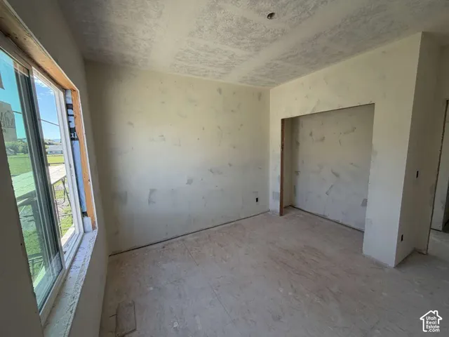 Unfinished interior space featuring a window, built-in wall niche, and unfinished flooring