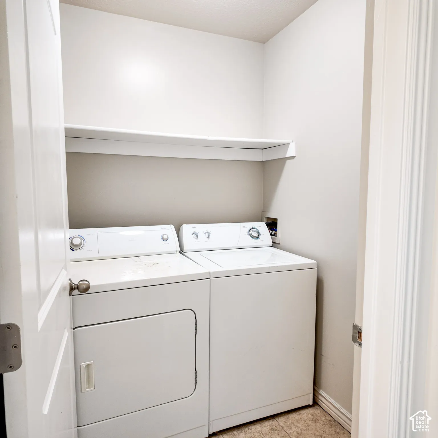 Laundry area with a built-in white shelf and tile flooring