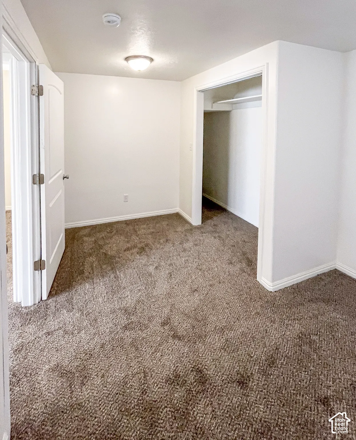 Wall-to-wall carpeting with a neutral tone, white walls, and a built-in closet