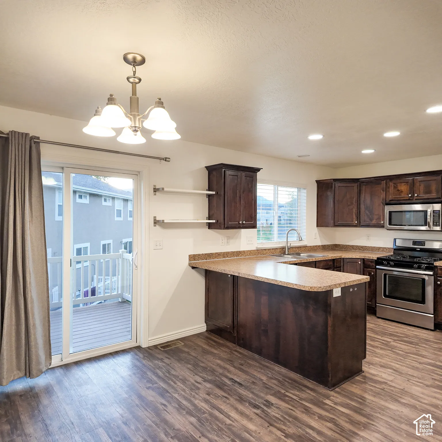 Kitchen featuring wood-finish flooring, dark wood cabinetry, stainless steel appliances, and a U-shaped countertop