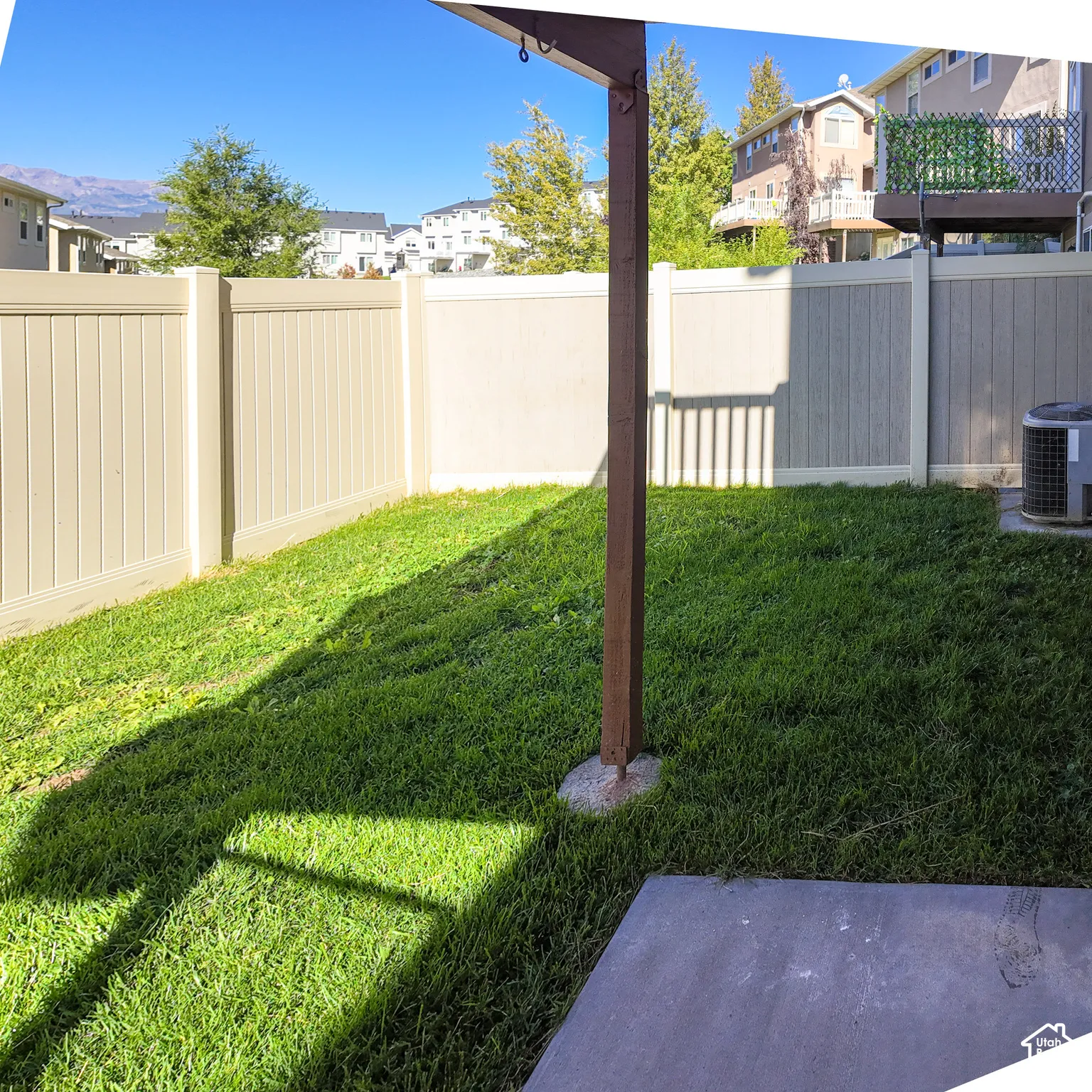 Fenced outdoor area featuring a concrete patio slab and a grass lawn