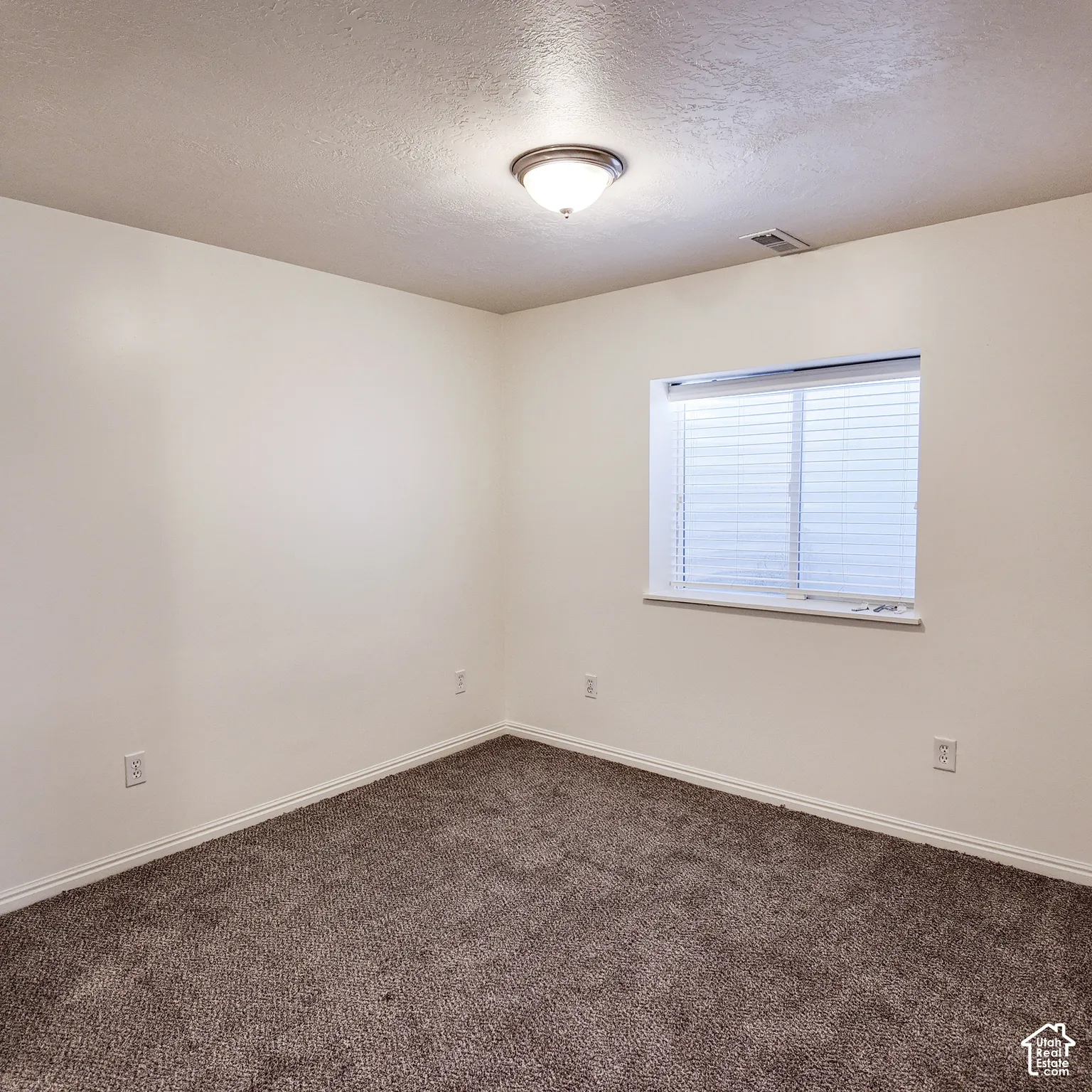 Neutral tone walls with textured ceilings, complete with a flush-mount ceiling light fixture