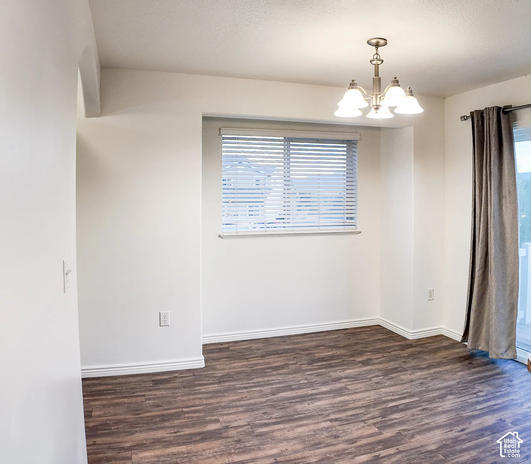 Wood-finish flooring, white walls, window with blinds, and a sliding glass door