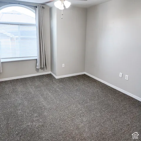 Arched window with blinds, ceiling fan with integrated lighting, and neutral wall paint