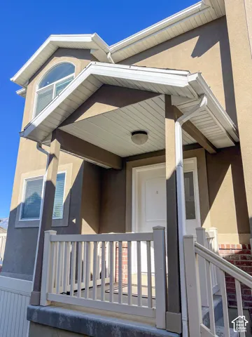 Covered entry with white porch railing, arched window, and stucco exterior