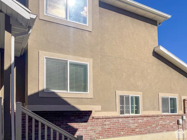 Stucco exterior with brick veneer accent, multiple windows, and white eaves