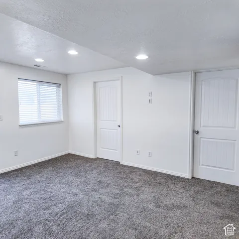 Recessed lighting, gray textured carpeting, white walls, white doors with panel detailing, and a window with blinds