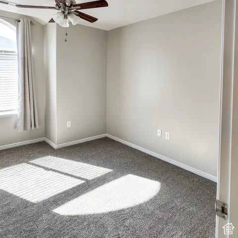 Neutral painted walls, gray carpet, and a ceiling fan with light fixture