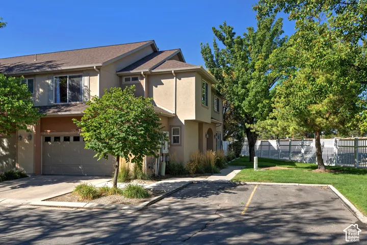 Multi-story exterior with stucco siding, an attached garage, and a paved driveway