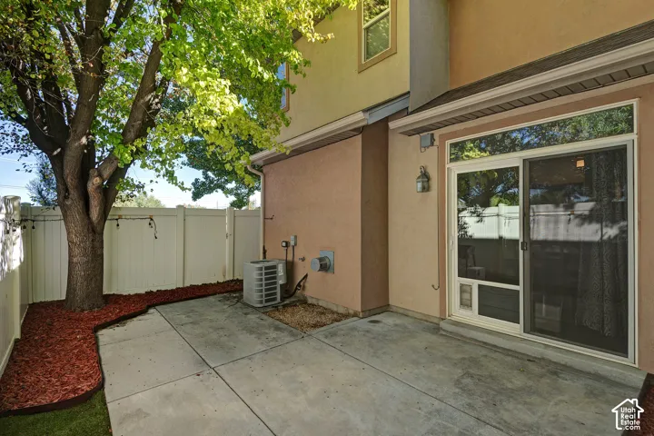 Private patio featuring concrete paving, a mature shade tree, and a full-height privacy fence