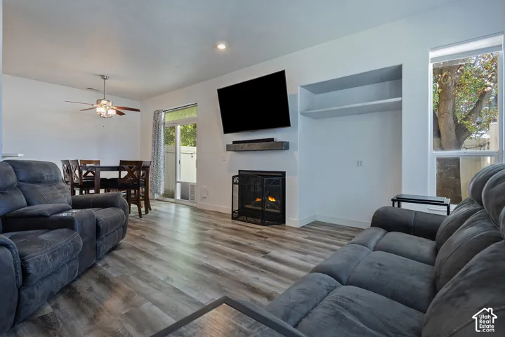 Wood-finish flooring throughout, featuring a fireplace with a mantel, built-in shelving, and a sliding glass door