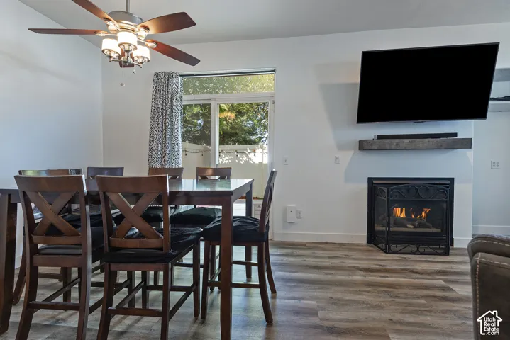 Open-concept living space with a built-in fireplace, wood-finish flooring, and a ceiling fan with integrated lighting