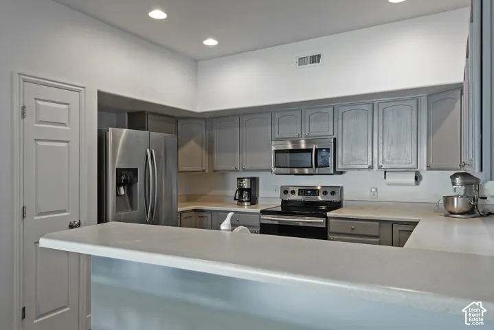 Kitchen featuring gray cabinetry, light-toned countertops, stainless steel appliances, and recessed lighting