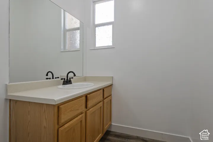 Vanity with a light wood-finish cabinet and countertop, undermount sink, and matte black faucet