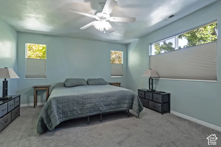 Recessed ceiling fan with light fixture, multiple windows with cellular shades, and wall-to-wall carpeting