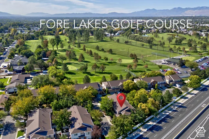 Property situated alongside a golf course, featuring established trees, residential structures, and a roadway