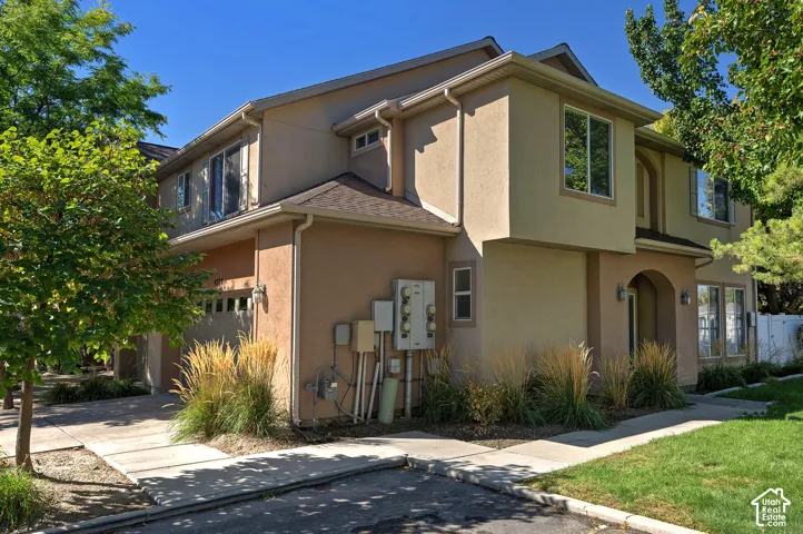 Multi-story stucco exterior with an arched entryway, attached garage, and mature landscaping