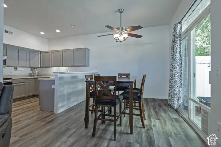 Wood-finish flooring throughout, ceiling fan with light fixture, gray cabinetry, sliding glass door, and recessed lighting