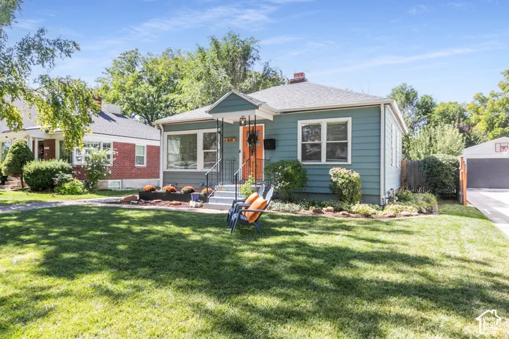 Exterior featuring siding, a front porch with railing, a paved driveway, and landscaping