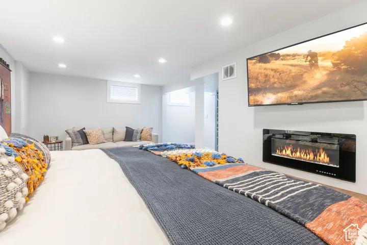 Recessed lighting, light gray walls, window with blinds, and built-in electric fireplace