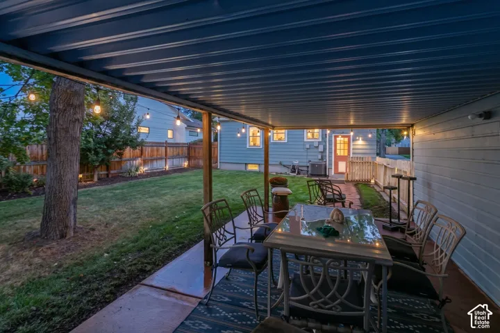 Covered patio with a corrugated metal ceiling, concrete flooring, and string lighting