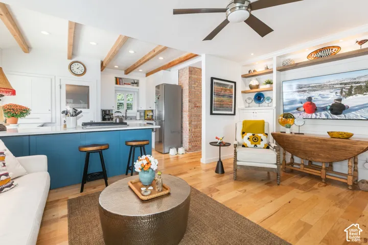 Hardwood flooring, exposed ceiling beams, recessed lighting, built-in shelving, and a ceiling fan