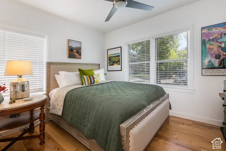 Hardwood flooring, ceiling fan, white window blinds, and multiple windows
